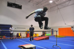 Teen boy jumping over gym bar