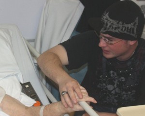 Grandson holds Grandmother's hand in hospital