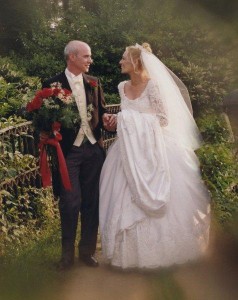 Bride and groom on a bridge, couple on bridge, smiling newlyweds on bridge, groom holds bouquet, groom holds roses