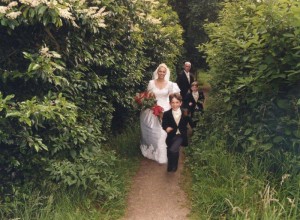 Bride, groom, boys running with bride and groom through path