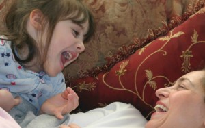 Daughter and mom laughing, mom and daughter being silly on couch, giggling and having fun